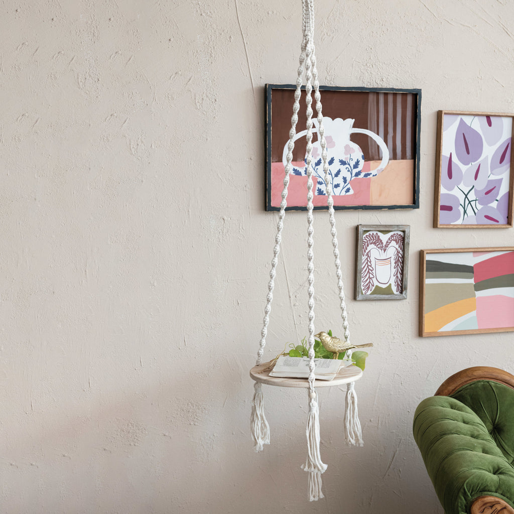 Wood & Cotton Macrame Plant Hanger/Shelf in front of wall with abstract floral prints and green couch