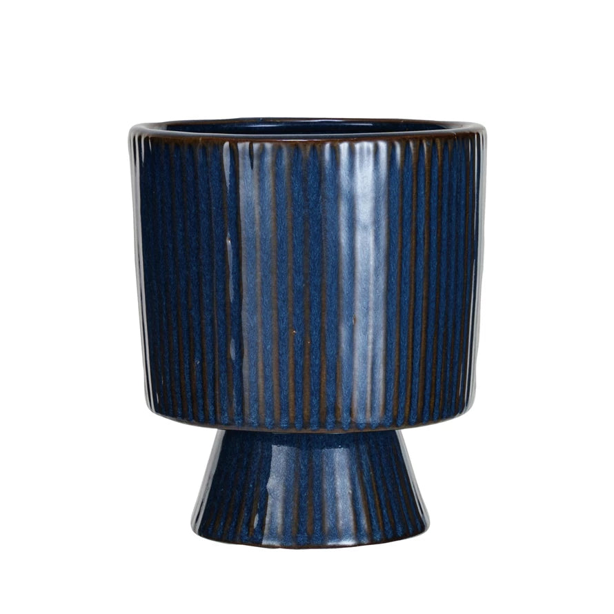Dark blue glazed fluted planter with pedestal and brown undercolor .