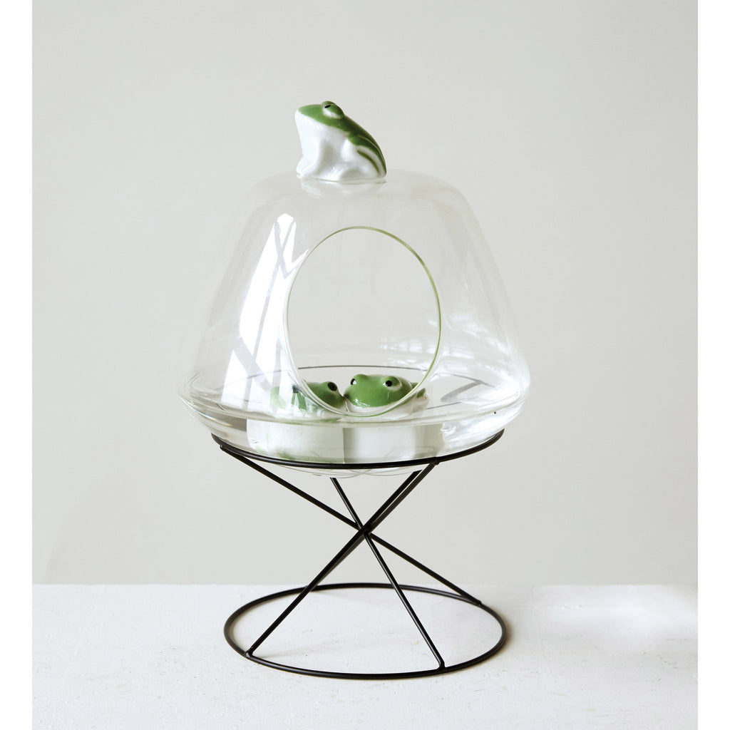 Stoneware Floating Frogs in glass terrarium on black round stand.