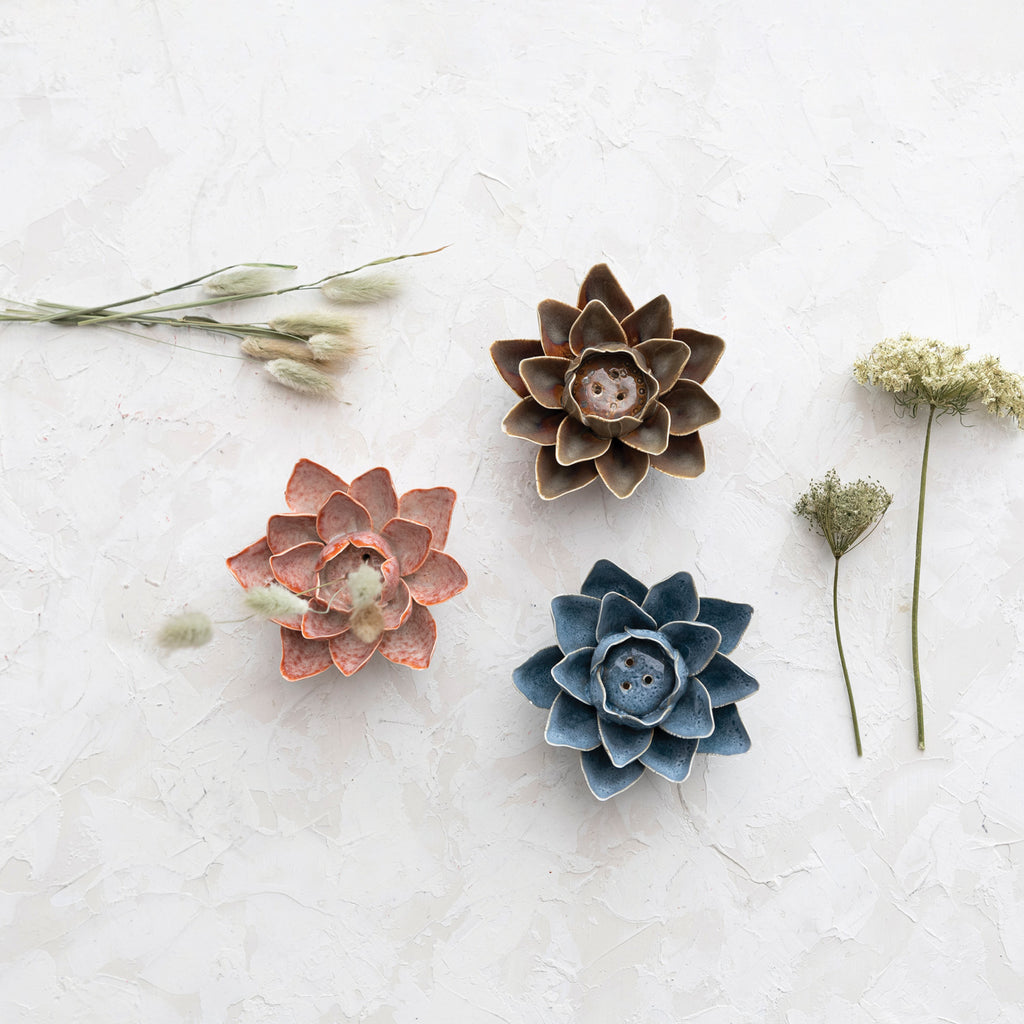 3 Handmade Stoneware Flower Incense Holders in Pink, Brown, and Blue surrounded by dry flowers.