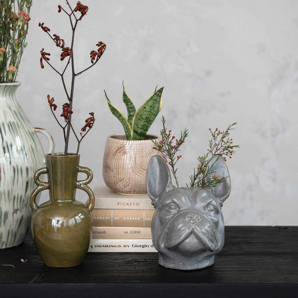 French Bulldog Vase on table with books, decorative vases, flowers and a plant.
