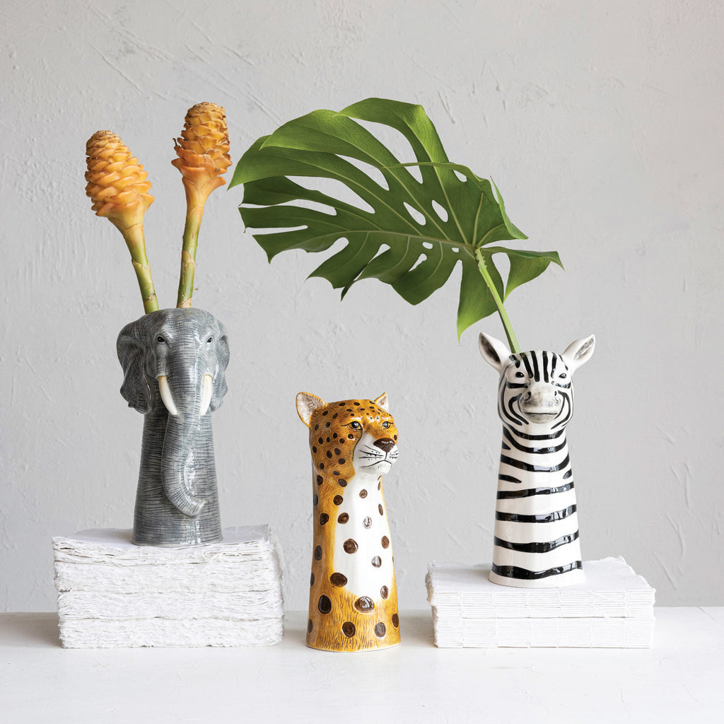 Zebra, elephant, and cheetah Hand-Painted Stoneware Vases with tropical stems inside on stacks of white paper and white background