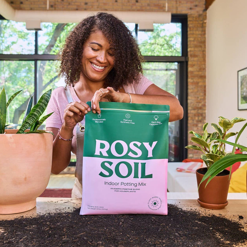 Girl re-sealing an 8qt bag of Rosy Soil potting mix