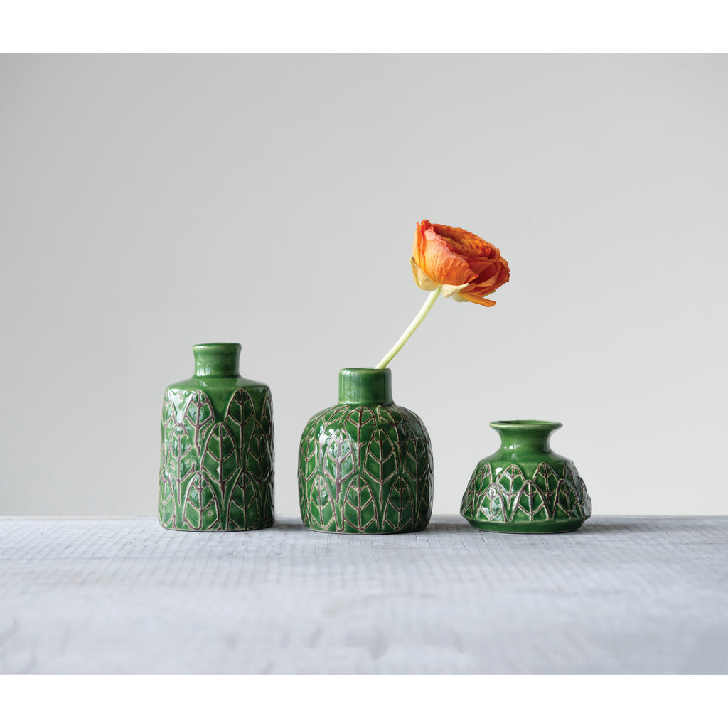 3 Green Embossed Stoneware Vases from tallest to shortest and orange ranunculus flower on grey table.